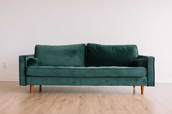 A comfortable green velvet couch in a warm, light-filled room