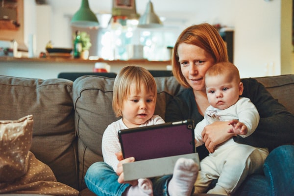 A mother sitting on a couch with her two young children, sharing a warm moment